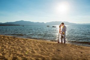 bride and groom kissing on beach, backlit, sun flare – South Lake Tahoe lakefront beach wedding nina photographer