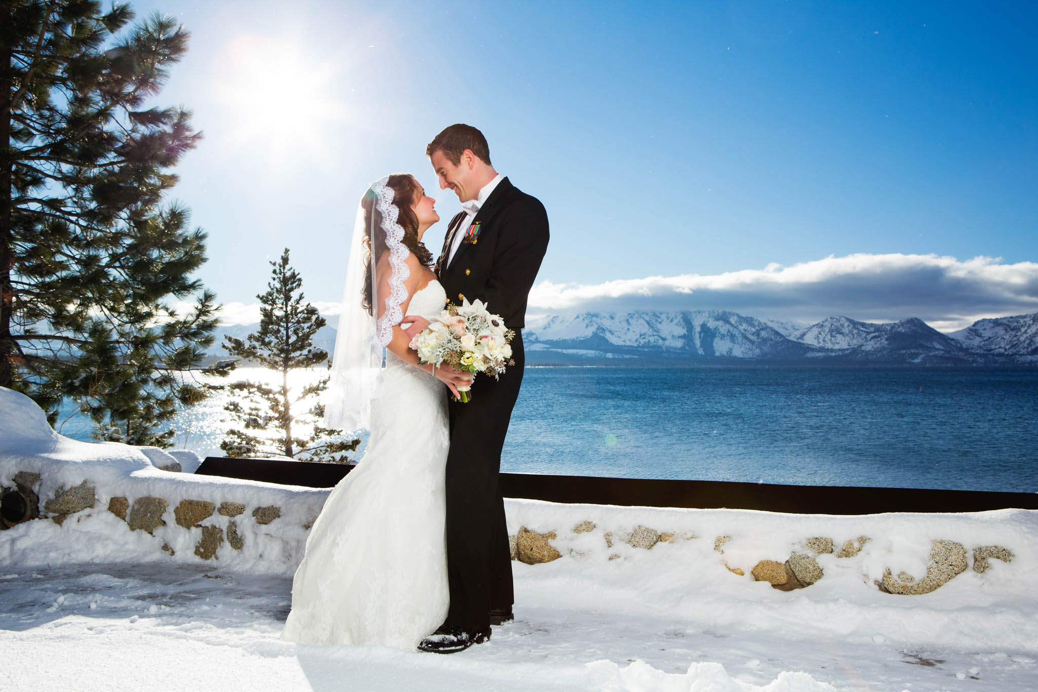 bride and groom portrait looking at each other, uniform, lake view, snow, white bouquet, lace, veil