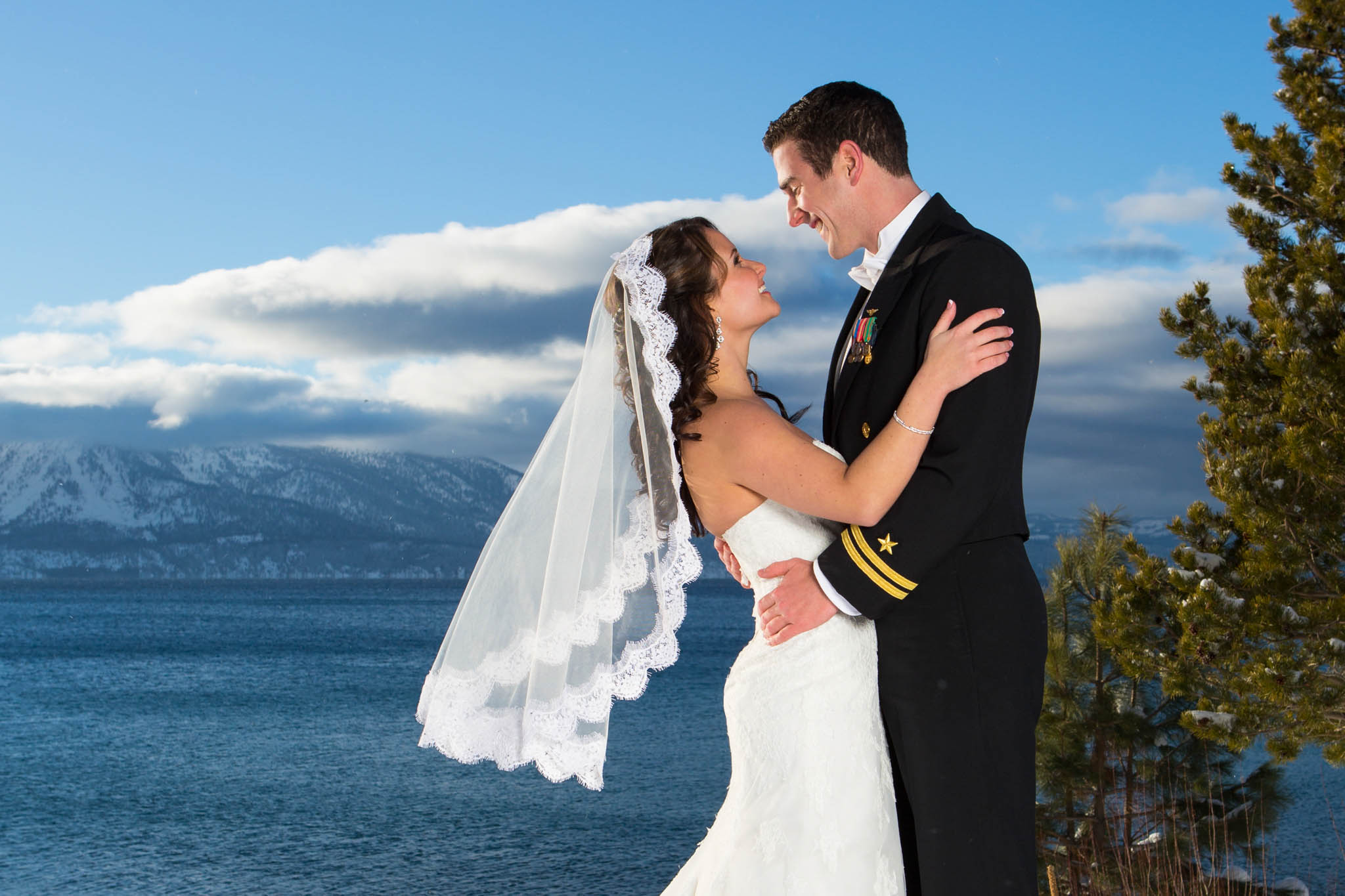 bride and groom portrait, smiling, looking at each other, veil flying, lake, blue, snow, winter, uniform
