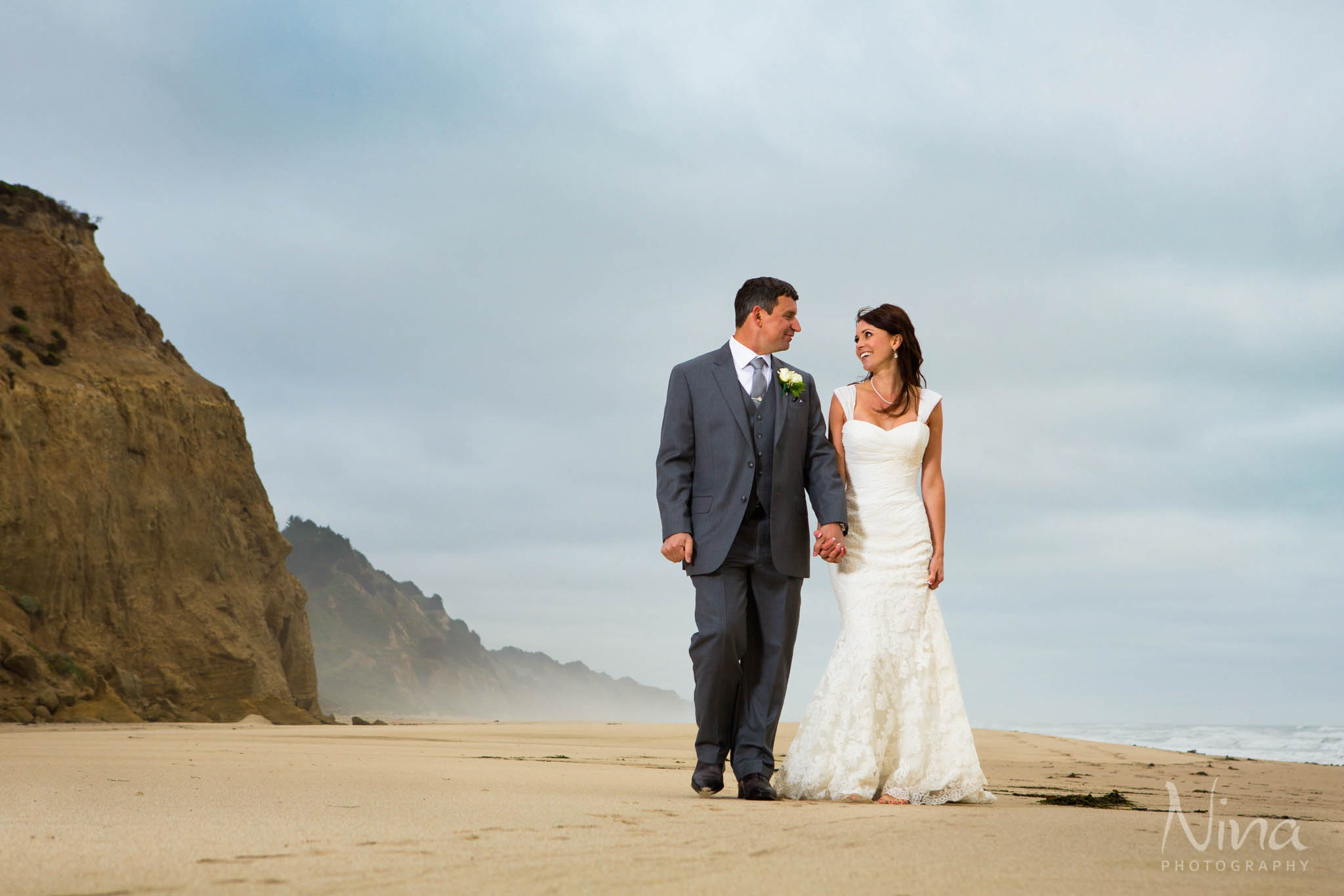 bride groom walking on beach ocean portrait photography