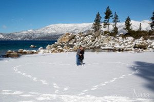couple making snow heart on beach, footprints in snow, kissing
