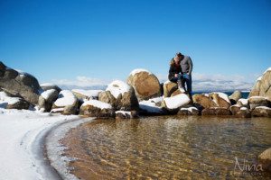 beach couple portrait kissing on rocks, blue lake, blue sky, mountains