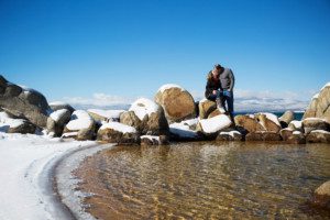 beach couple portrait kissing on rocks, blue lake, blue sky, mountains