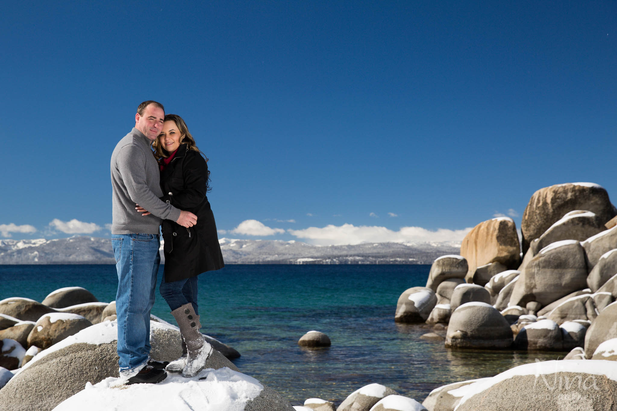 beach couple portrait on rocks, blue lake, blue sky, mountains
