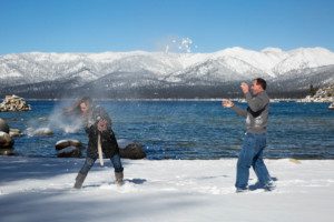 couple snow fight on beach, laughing, blue lake, blue sky, fun, mountains